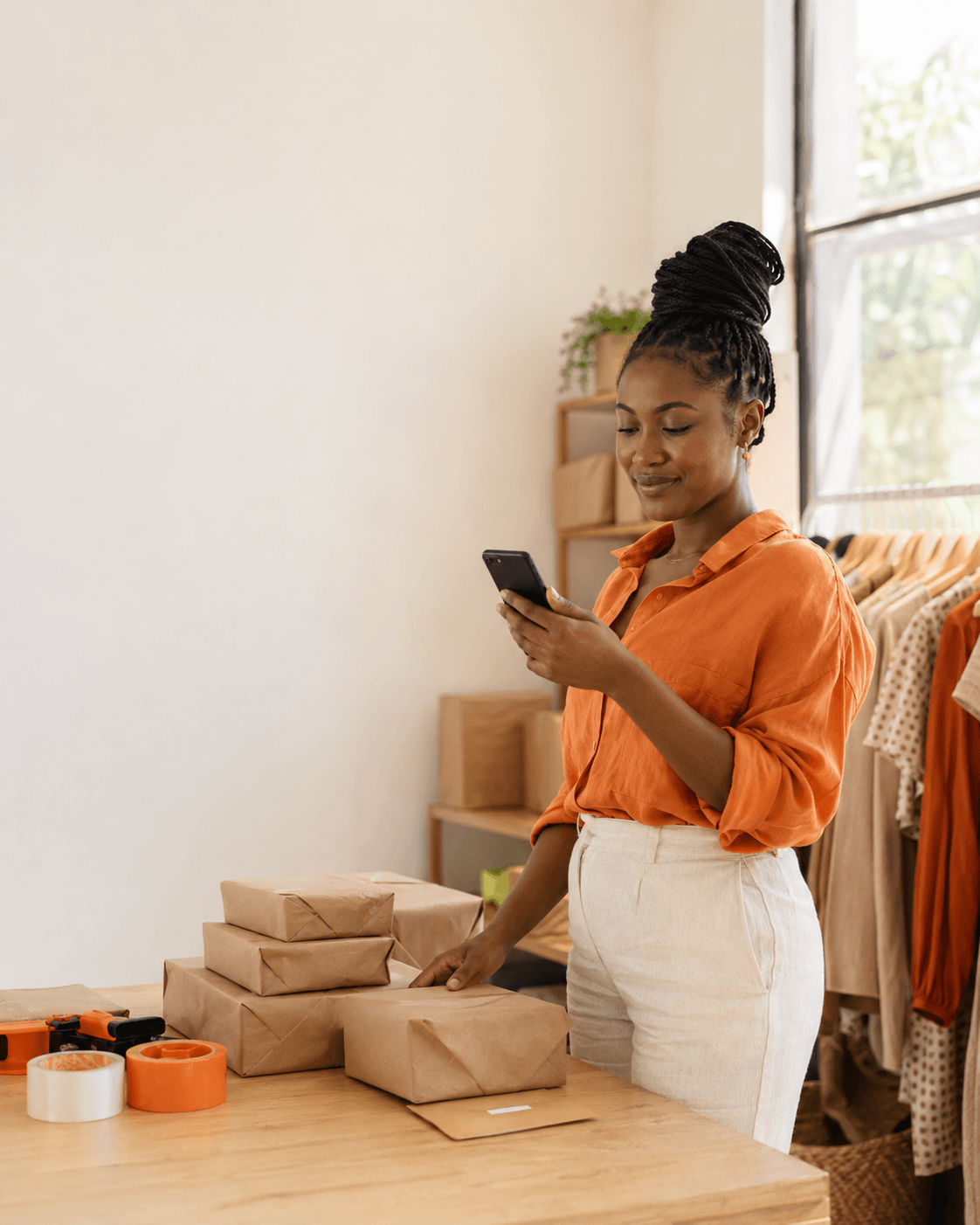 A Nigerian merchant checking an order on her phone while packing parcels